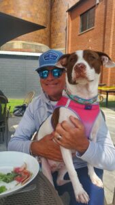 man holding brown and white dog at an outdoor cafe